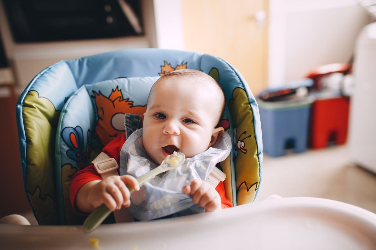 Bébé dégustant sa première céréale bébé à la cuillère lors de la diversification alimentaire