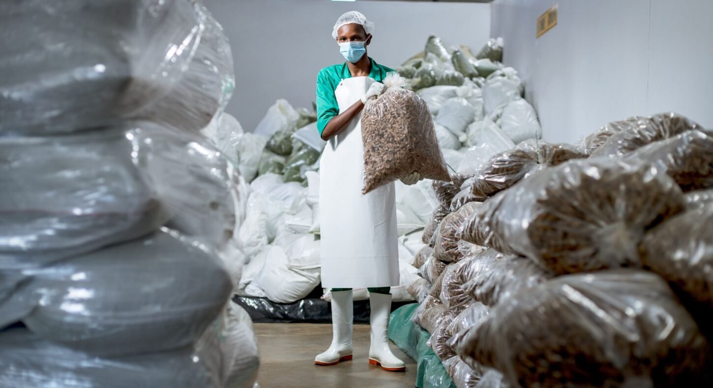 Travailleur en protection tenant des sacs de produits alimentaires en gros dans un entrepôt africain